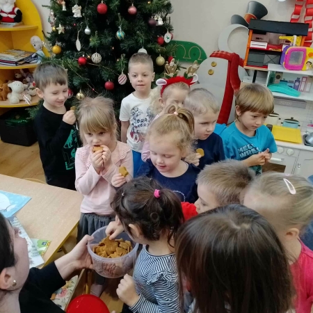 Fotografia kolorowa. Czas na słodki poczęstunek. Dzieci próbują pierniczków. 