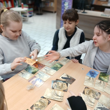 Fotografia kolorowa. Dzieci grają w planszówki w bibliotece w Górkach Małych.