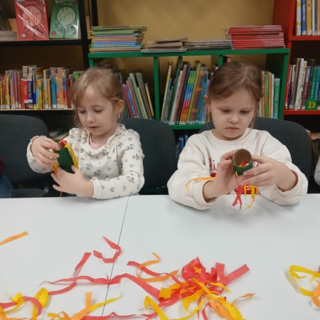 Fotografia kolorowa. Przedszkolaki wykonują prace plastyczne w bibliotece w Górkach Małych. 
