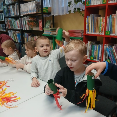 Fotografia kolorowa. Przedszkolaki wykonują prace plastyczne w bibliotece w Górkach Małych. 