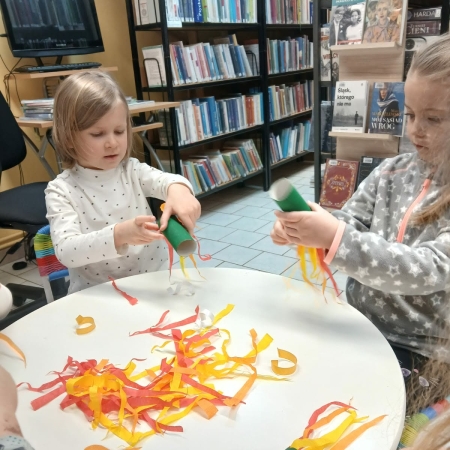 Fotografia kolorowa. Przedszkolaki wykonują prace plastyczne w bibliotece w Górkach Małych. 