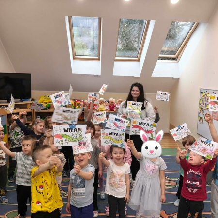 Fotografia kolorowa. Zdjęcie grupowe z wykonanymi flagami z napisem Witaj Wiosno! 