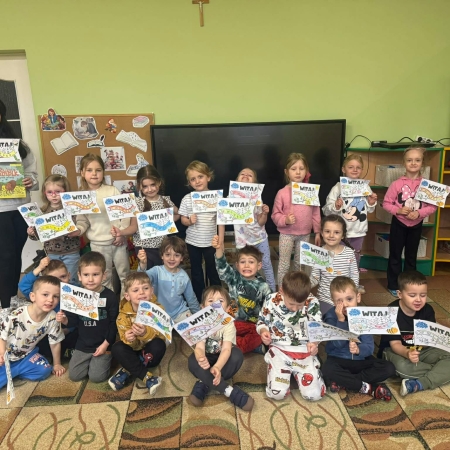 Fotografia kolorowa. Zdjęcie grupowe z wykonanymi flagami z napisem Witaj Wiosno! 